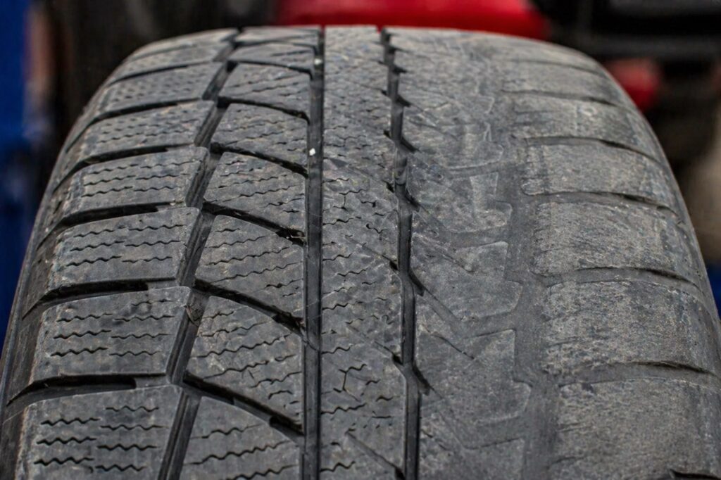 Close-up of winter tire tread showing wear patterns from warm weather driving in Kamloop