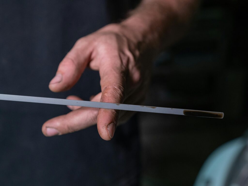 Close-up of a person checking engine oil level on a dipstick with dark oil visible near the tip.